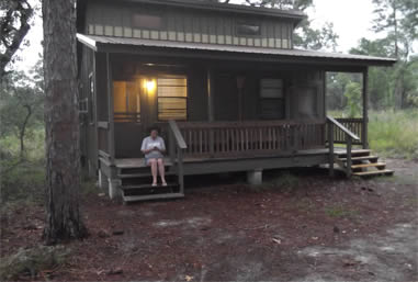 A lone girl sits on the steps of her cabin.